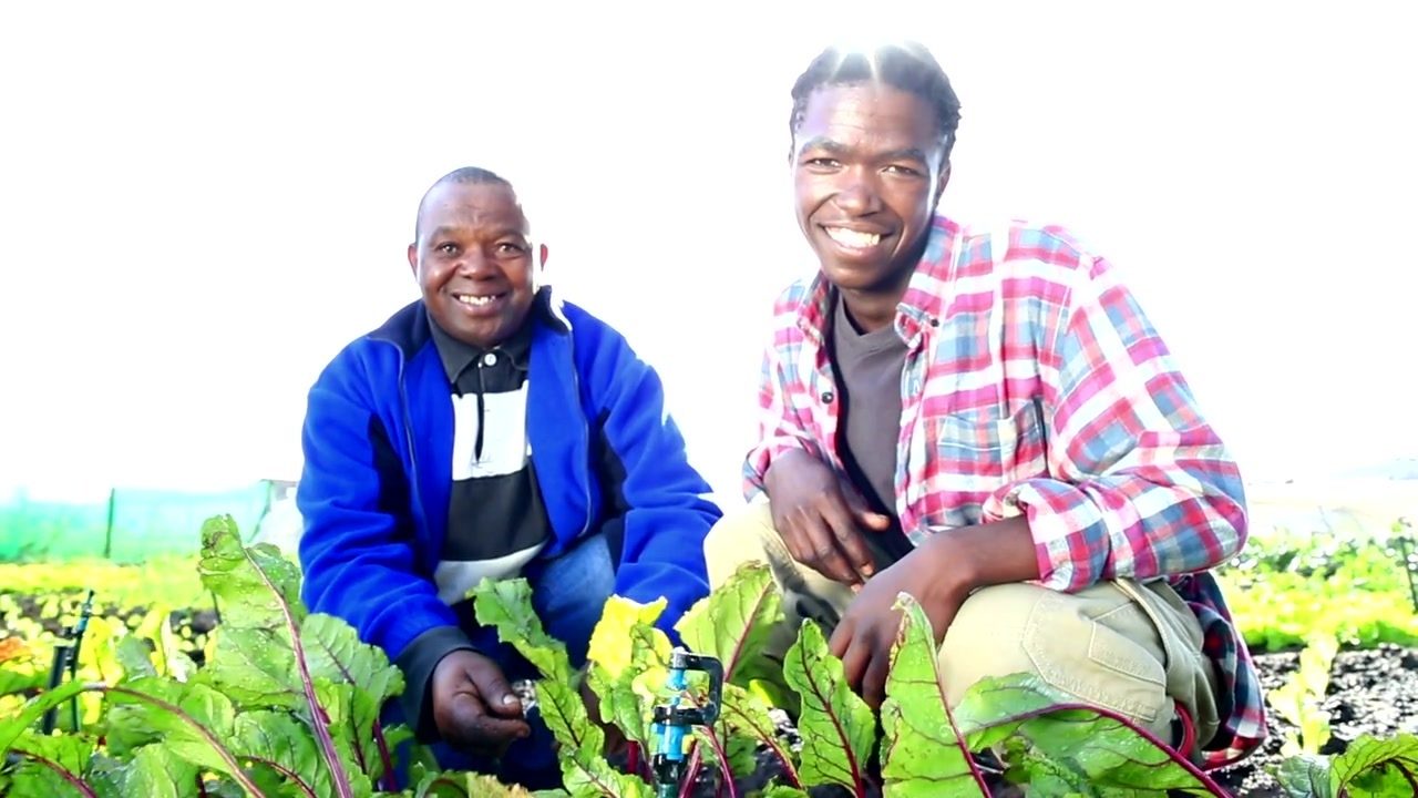 Two men smiling together in a cultivated field